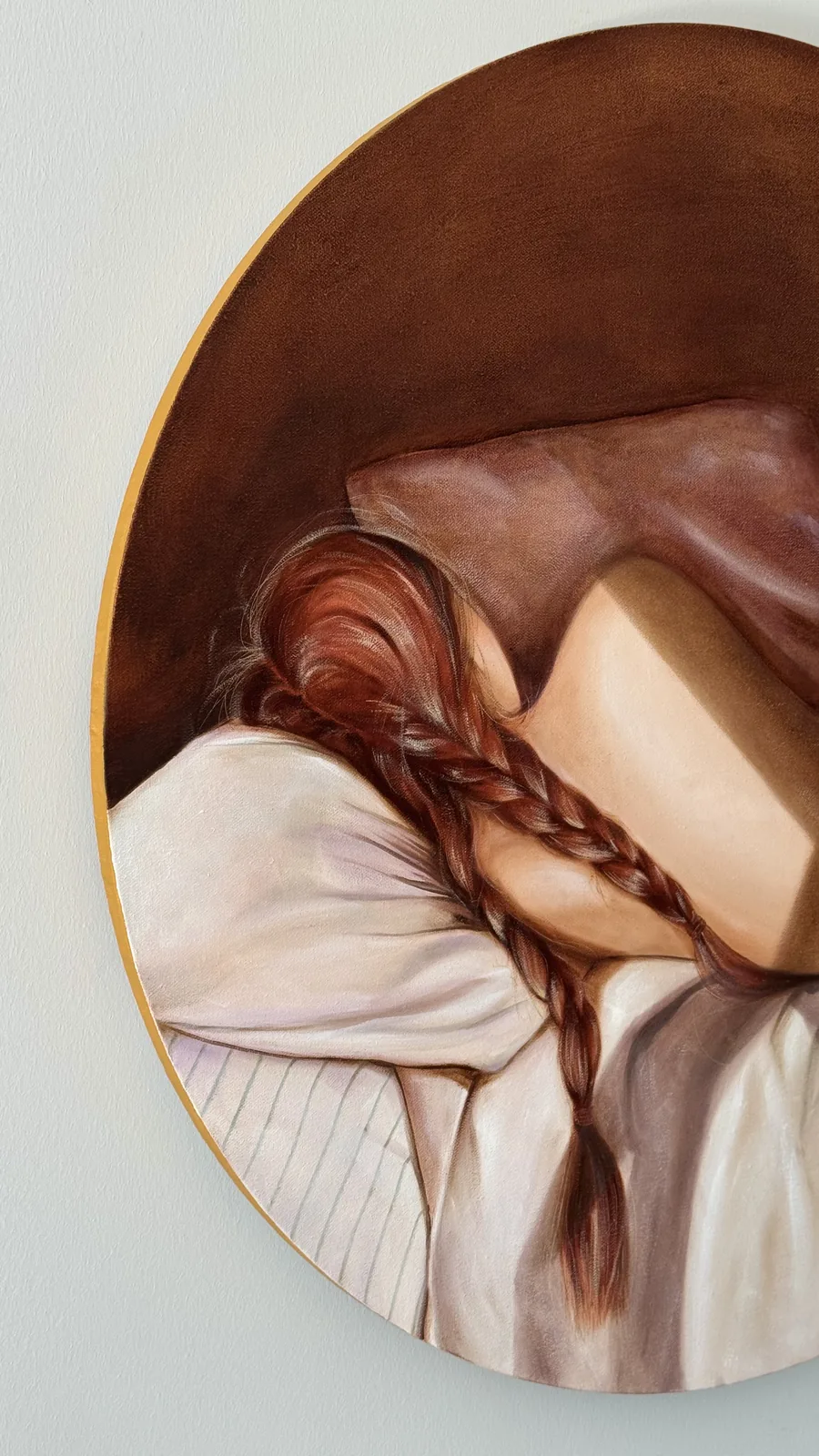 The round canvas photographed close: the gilded edge of the tondo is visible