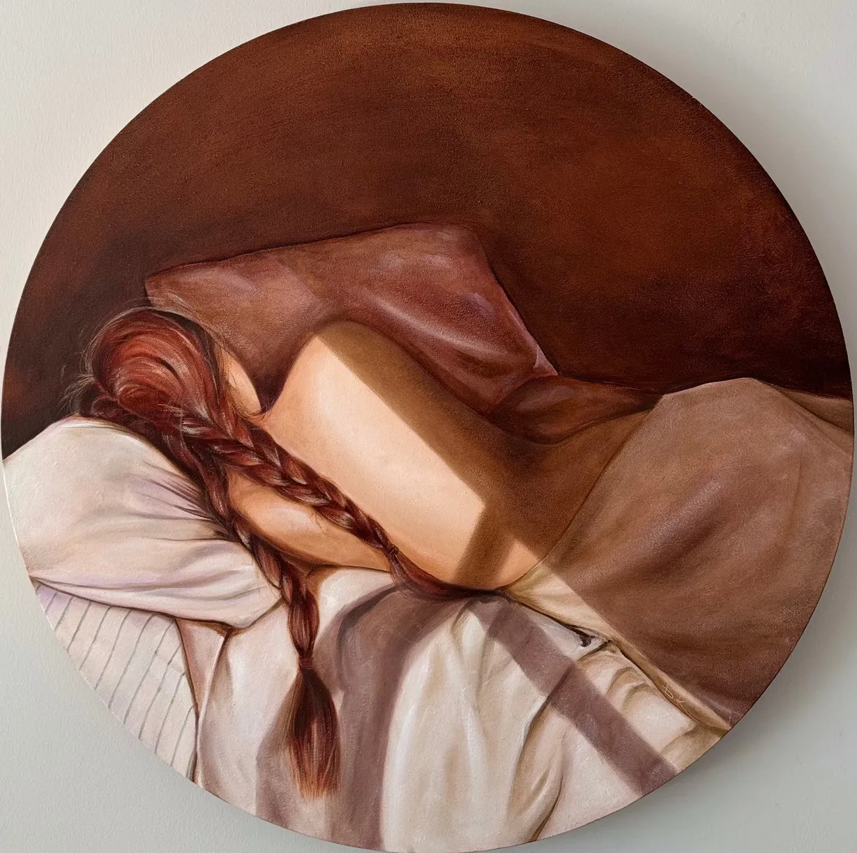 Round canvas: a sleeping figure with a braid among warm folded sheets