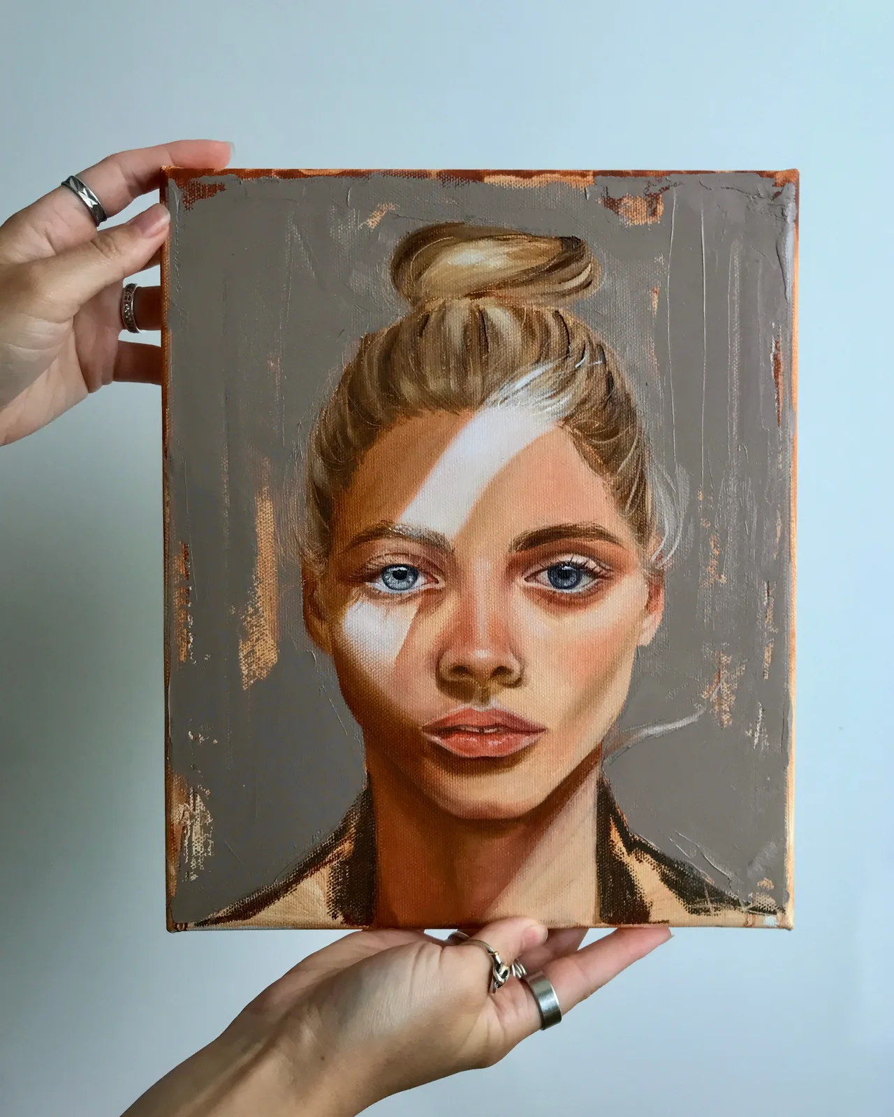 The canvas held in two hands, showing its true size and the painted edges